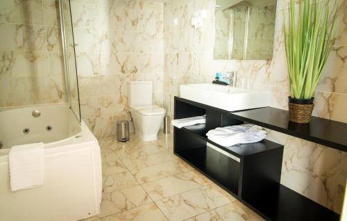 a bathroom with a tub and a sink and a toilet at Hotel Muchacho in Macedo de Cavaleiros