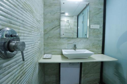 Hotel Paramount Inn في راجكوت: حمام مع حوض ومرآة