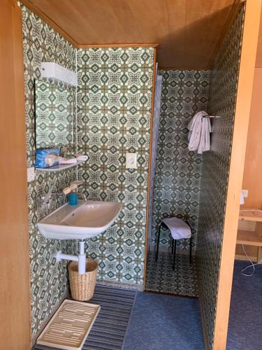 a small bathroom with a sink and a chair at Hotel Wildhorn in Lauenen