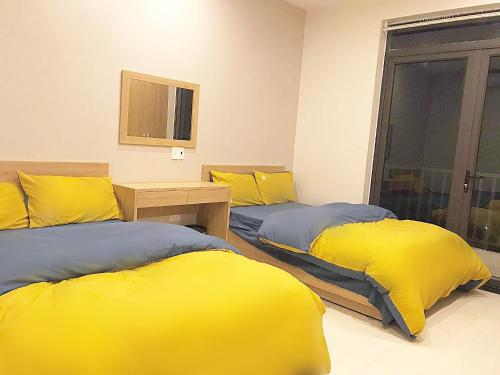 two beds with yellow pillows in a room at Hong Hao Hostel and Motorbikes in Ha Giang