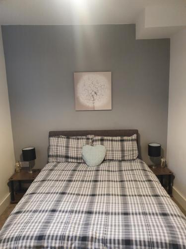 a bed with a plaid bedspread and a heart pillow at St Leonards cottage in Newark upon Trent