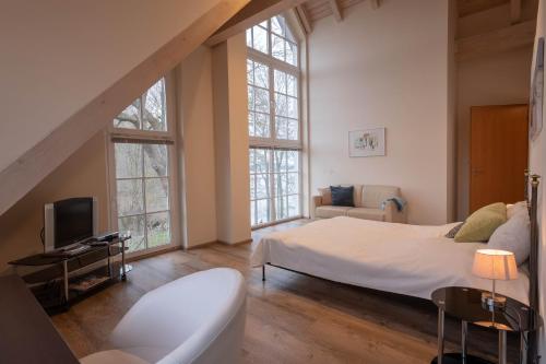 a bedroom with a bed and a couch and windows at Herrenhaus Jürgenshof - Ferienhaus in Alt Schwerin