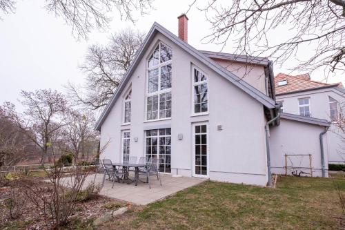 a white house with a table on a patio at Herrenhaus Jürgenshof - Ferienhaus in Alt Schwerin