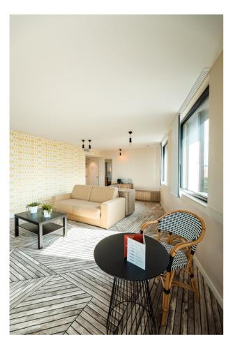 ein Wohnzimmer mit Sofa und Tisch in der Unterkunft The Originals Boutique, Hôtel Maison Montmartre Paris Les Puces in Paris