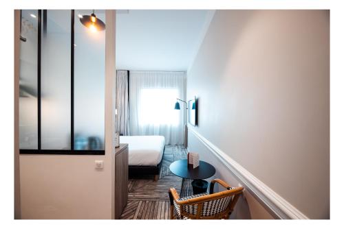 ein kleines Zimmer mit einem Bett, einem kleinen Tisch und einem Stuhl in der Unterkunft The Originals Boutique, Hôtel Maison Montmartre Paris Les Puces in Paris