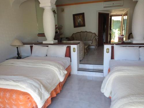 two beds in a room with a living room at Gran Hotel Hacienda De La Noria in Aguascalientes