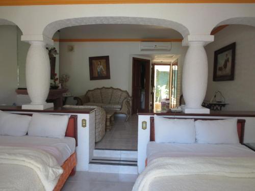 two beds in a room with a living room at Gran Hotel Hacienda De La Noria in Aguascalientes