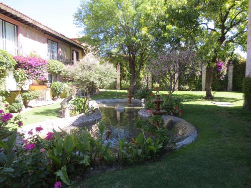 a garden with a pond in front of a house at Gran Hotel Hacienda De La Noria in Aguascalientes