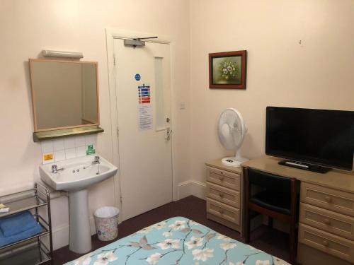 a bathroom with a sink and a tv and a bed at St. James's Guest House in London