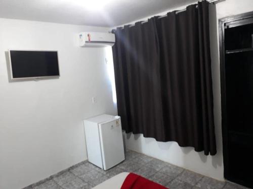 Mundial Hotel في غويانيا: غرفة فيها تلفزيون وستارة سوداء