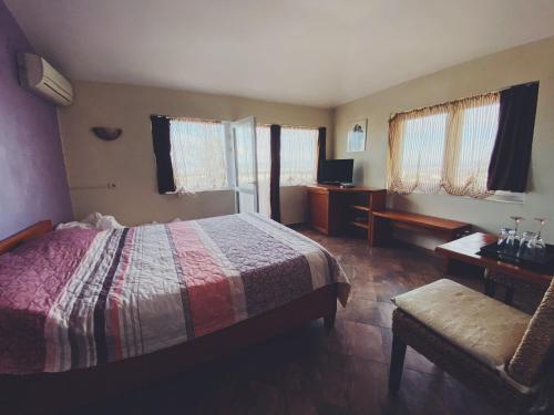 a bedroom with a bed and a chair and windows at Hotel Fancy in Sofia