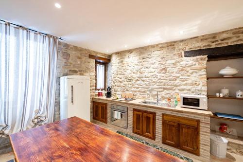 a kitchen with a wooden table and a stone wall at Mamihouse in Gubbio