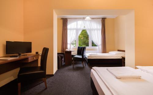una camera d'albergo con 2 letti, una scrivania e una TV di Toreja a Karpacz