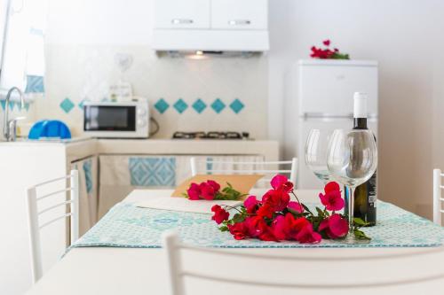 a table with red flowers and a wine glass at Residence Fior di Sulcis in Calasetta