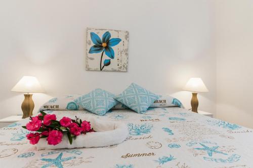 a bed with pink flowers on it with two lamps at Residence Fior di Sulcis in Calasetta