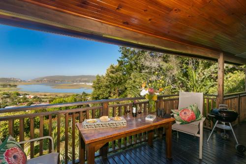 a table on a deck with a view of a river at Big Tree House Lodge in Knysna