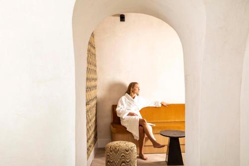 a woman sitting on a bed under an archway at Hotel Phileas Lazare & Spa - Opera in Paris