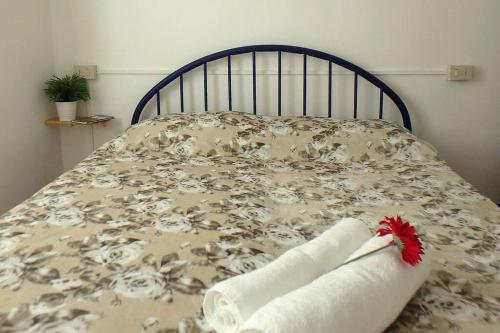 un letto con una coperta con un fiore rosso sopra di Nettuno 1A a Lido di Pomposa