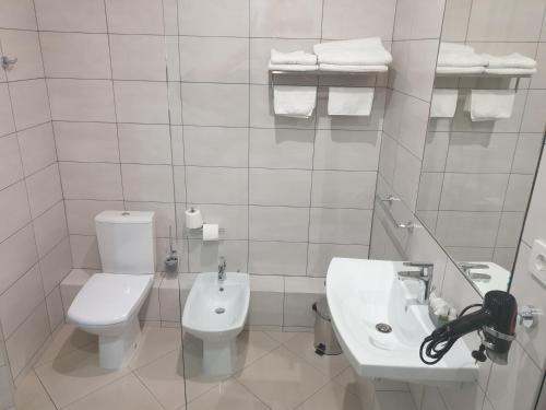 a white bathroom with a toilet and a sink at LEX Trend Hotel in Irpin'