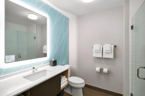 a bathroom with a toilet a sink and a mirror at avid hotels - Boston Logan Airport - Revere, an IHG Hotel in Revere