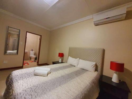 a bedroom with a large white bed with two lamps at Tenacity Guesthouse - Riviera Park in Mahikeng