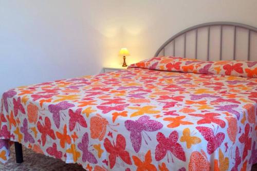 a bed with a colorful comforter on top of it at Nettuno 9C in Lido di Pomposa