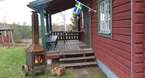 a porch of a red house with a wood stove at Ekesberget Stugby stuga 3 in Ekshärad