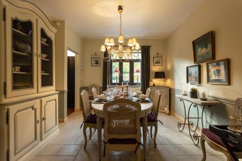 a dining room with a table with chairs and a chandelier at Riverside Cottage Dinant in Dinant