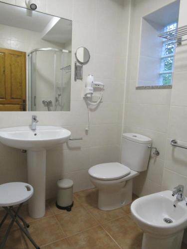 a white bathroom with a sink and a toilet at Apartamentos El Haya in Cosgaya