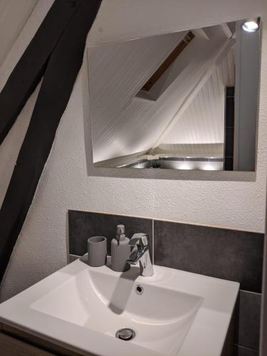 a bathroom with a white sink and a mirror at Numéro 7 in Le Tronquay