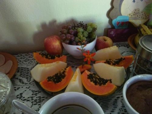 a table topped with slices of fruit and a bowl of grapes at Pousada da Carmem in Visconde De Maua