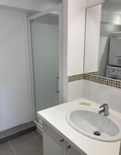 La salle de bains blanche est pourvue d'un lavabo et d'un four micro-ondes. dans l'établissement Les Cyprès - Appt avec terrasse proche plage, à Saint-Malo