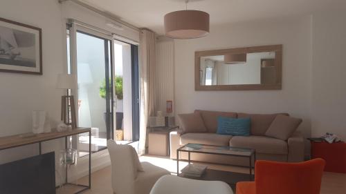 een woonkamer met een bank en een spiegel bij Les Cyprès - Appt avec terrasse proche plage in Saint-Malo