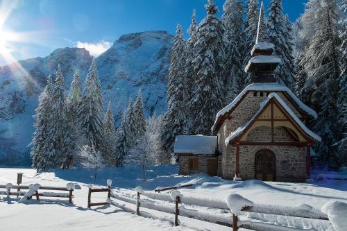 a small church in the snow with a fence at Hotel Edelweiss in Braies