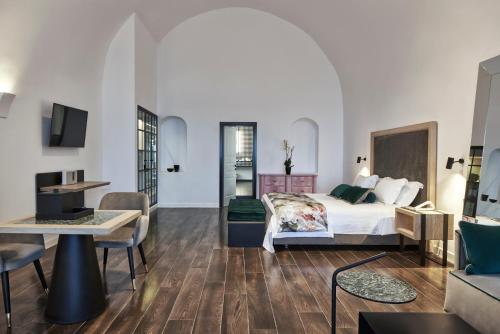 a bedroom with a bed and a living room at Katikies Garden Santorini - The Leading Hotels Of The World in Fira