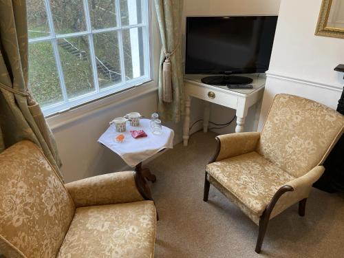 a living room with two chairs and a table and a television at Tall Storeys in Scarborough