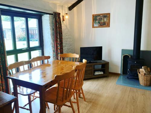 une salle à manger avec une table, des chaises et une cheminée dans l'établissement Shire Cottage - Crackington Haven, Cornwall, à Saint Gennys