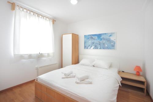 a white bedroom with a large bed with white sheets at Vila Bjanka in Zlatibor