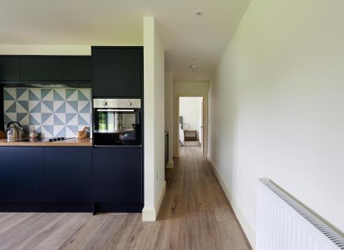 a kitchen with black cabinets and a white wall at The Cabin in Haverfordwest