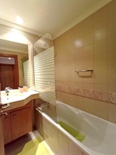 a bathroom with a tub and a sink and a mirror at Garden's Apartment in Funchal