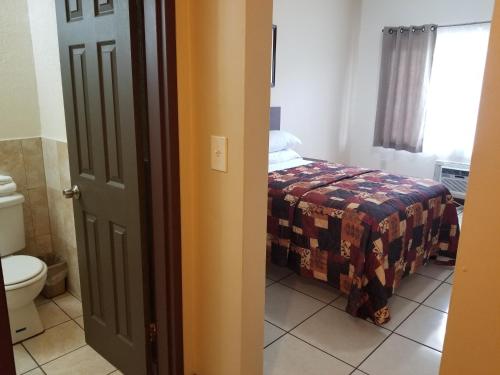 une salle de bain avec un lit et des toilettes dans une chambre dans l'établissement Parkway Inn, à Miami