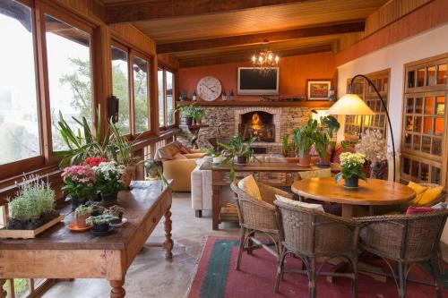 a living room with tables and chairs and a fireplace at Pousada Benevento in Campos do Jordão