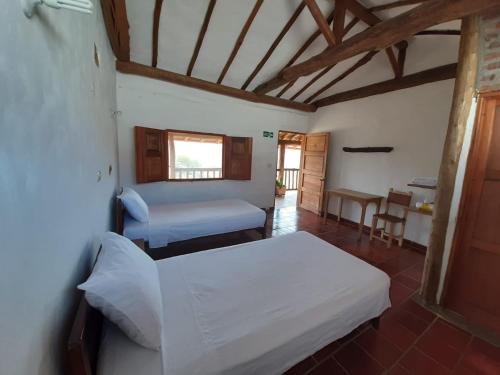 um quarto com 2 camas, uma mesa e uma janela em Artepolis em Barichara