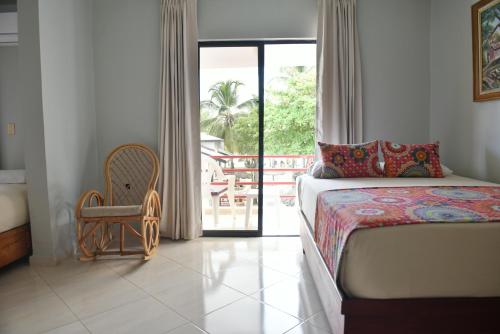 a bedroom with a bed and a chair and a balcony at Hotel Zapata in Boca Chica