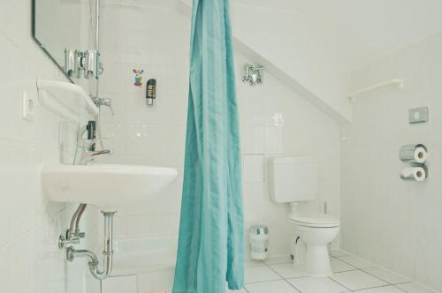 uma casa de banho branca com um lavatório e um WC em Happy Hotel Berlin em Berlim