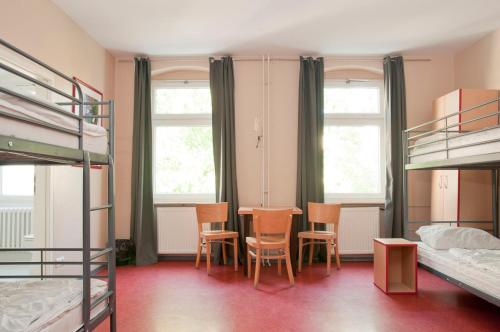 a room with a table and chairs and windows at Happy Hotel Berlin in Berlin