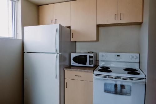 a kitchen with a white refrigerator and a microwave at SAIT Residence & Conference Centre - Calgary in Calgary