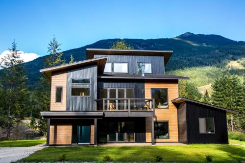 a house on a hill with mountains in the background at Arrows Edge Lodge in Revelstoke