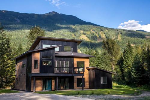 a house on a hill with mountains in the background at Arrows Edge Lodge in Revelstoke