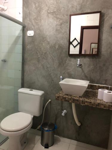 a bathroom with a toilet and a sink and a mirror at Lua Pousada in Barra de São Miguel